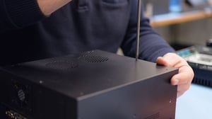 A worker is assembling a computer at Hatteland Technology's Sweden office. He is using a screw driver to mount the cabinet on an industrial computer.