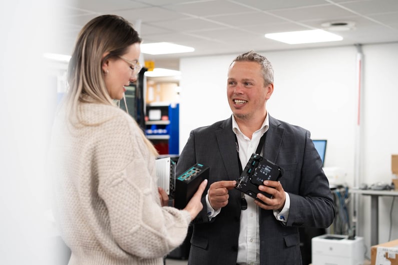 The picture shows Camilla Haglund and Gøran Labrå, from Hatteland Technology, holding and looking at Moxa switches..