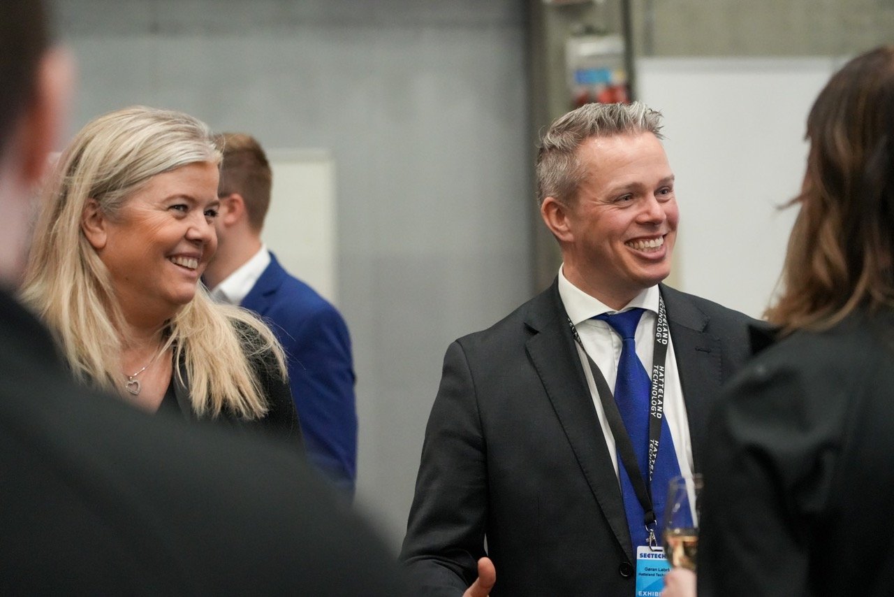 Monica Øyen and Gøran Labrå from Hatteland Technology at SecTech 2023, wearing suits, both smiling. 