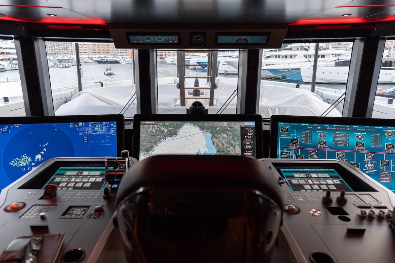 The image shows the view from the captain's chair on the bridge of superyacht Baglietto T52. Three floor-mounted 55-inch monitors by Hatteland Technology are in the centre of the picture. They are part of Furuno's integrated bridge system for the yacht market. In the background you can see many other yachts and part of the bay of Monaco. 
