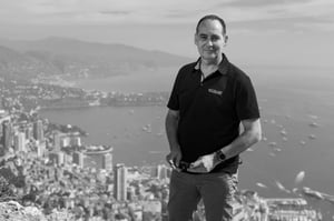The picture shows Mehdi Bounoua, Hatteland Technology's Sales Director for Europe, Middle East and Africa. Behind him is the bay of Monaco. He is wearing a black Hatteland Technology t-shirt, and faces the camera.