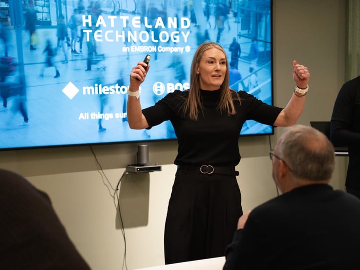 Tine Thorsen i Hatteland Technology står foran skjermen og presenterer. Anledningen er Bosch/Milestone-samling i Oslo i januar 2023. Hun er kledd i sort. Blå bakgrunn.