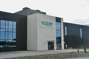 Hatteland Technology's headquarters in Aksdal, Norway, as seen from the front. The sky is grey. The parking lot is empty. The Hatteland Technology logo is in the middle of the picture, on the facade.
