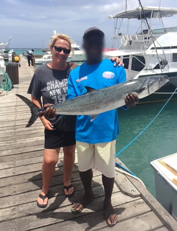Donna Pallonetti, office manager for the US branch of Hatteland Technology, is standing at a dock in Aruba. The captain of the fishing boat is next to her, holding a large fish they caught.