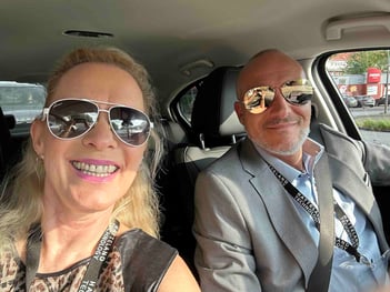 This picture shows Elke Freisens and Mario Largana-Domberg, the German team of Hatteland Technology. They are in a car. They are smiling and wearing sunglasses.