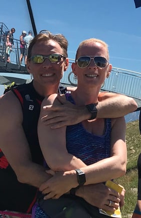 The picture shows Elke Freisens, senior sales rep at Hatteland Technology Germany, on a trail run with her husband. It's a sunny day. They are smiling, wearing sunglasses and looking at the camera. They are wearing sleeveless shirts. 