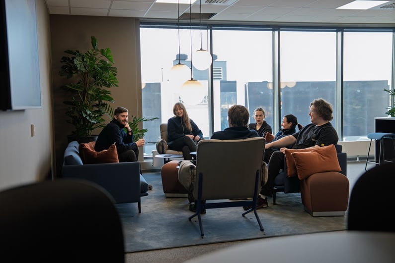 This picture shows Hatteland Technology staff in one of the communal areas inside the new production building. Another building is visible through the windows, in the background.