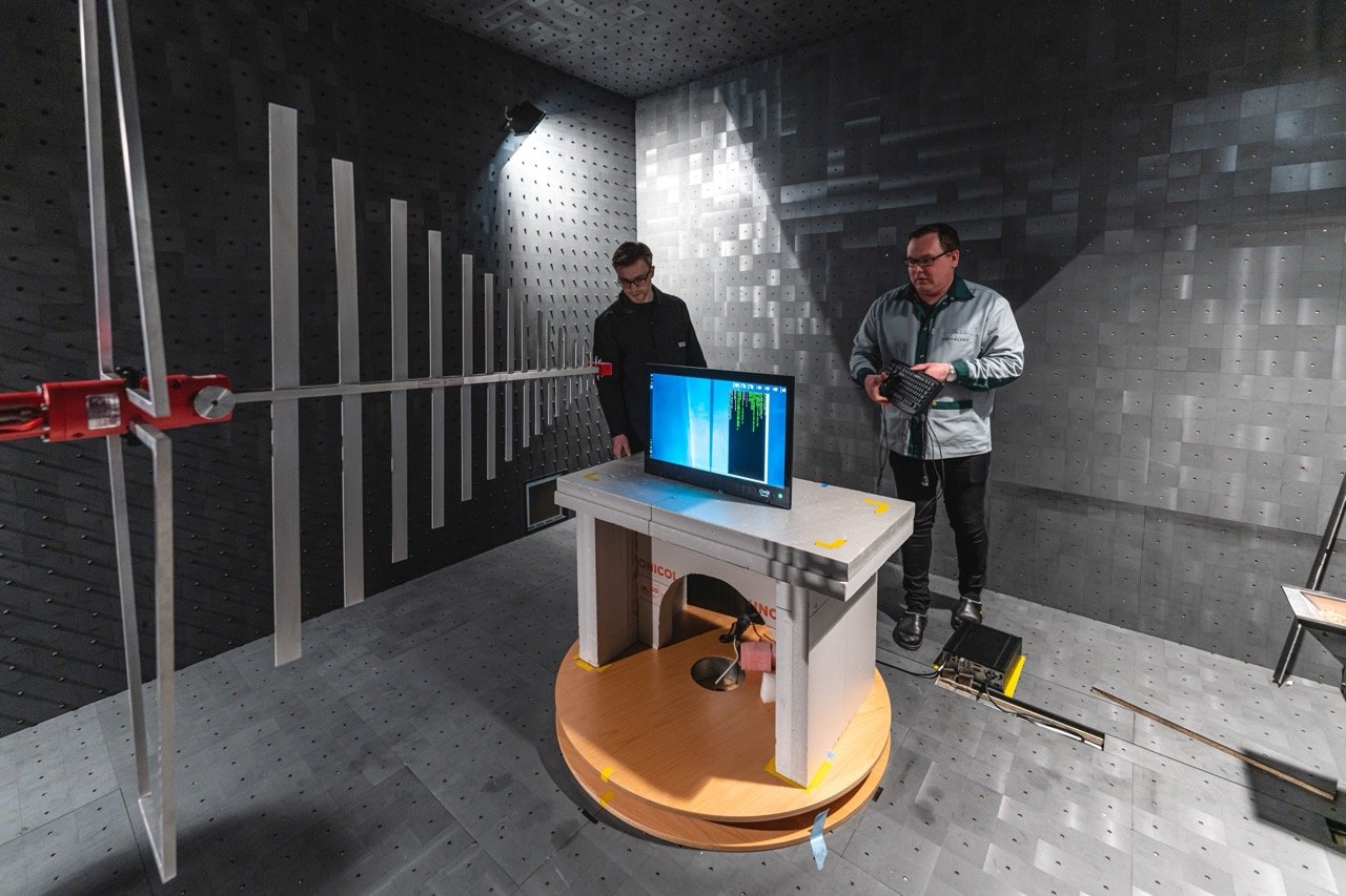 Two Hatteland Technology employees prepare a maritime monitor for testing in the EMC chamber. 