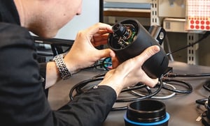 A worker is inspecting a Hatteland Technology Seahawk camera at the company HQ in Aksdal, Norway. He has opened the camera, exposing wires and optics.