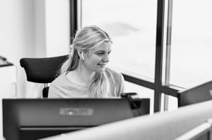 The image shows a Hatteland Technology employee behind the desk, talking on the phone. She is a customer service representative, helping a customer. She has long, blond hair and is smiling.