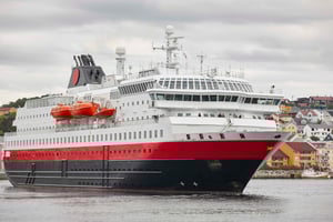 The image shows a passenger ship from one of the famous Norwegian cruise lines. The ship is black, red and white. We see the ship from the front, with the bridge and life boats visible. Hatteland Technology provided the CCTV solution for these ships when they were refurbished.