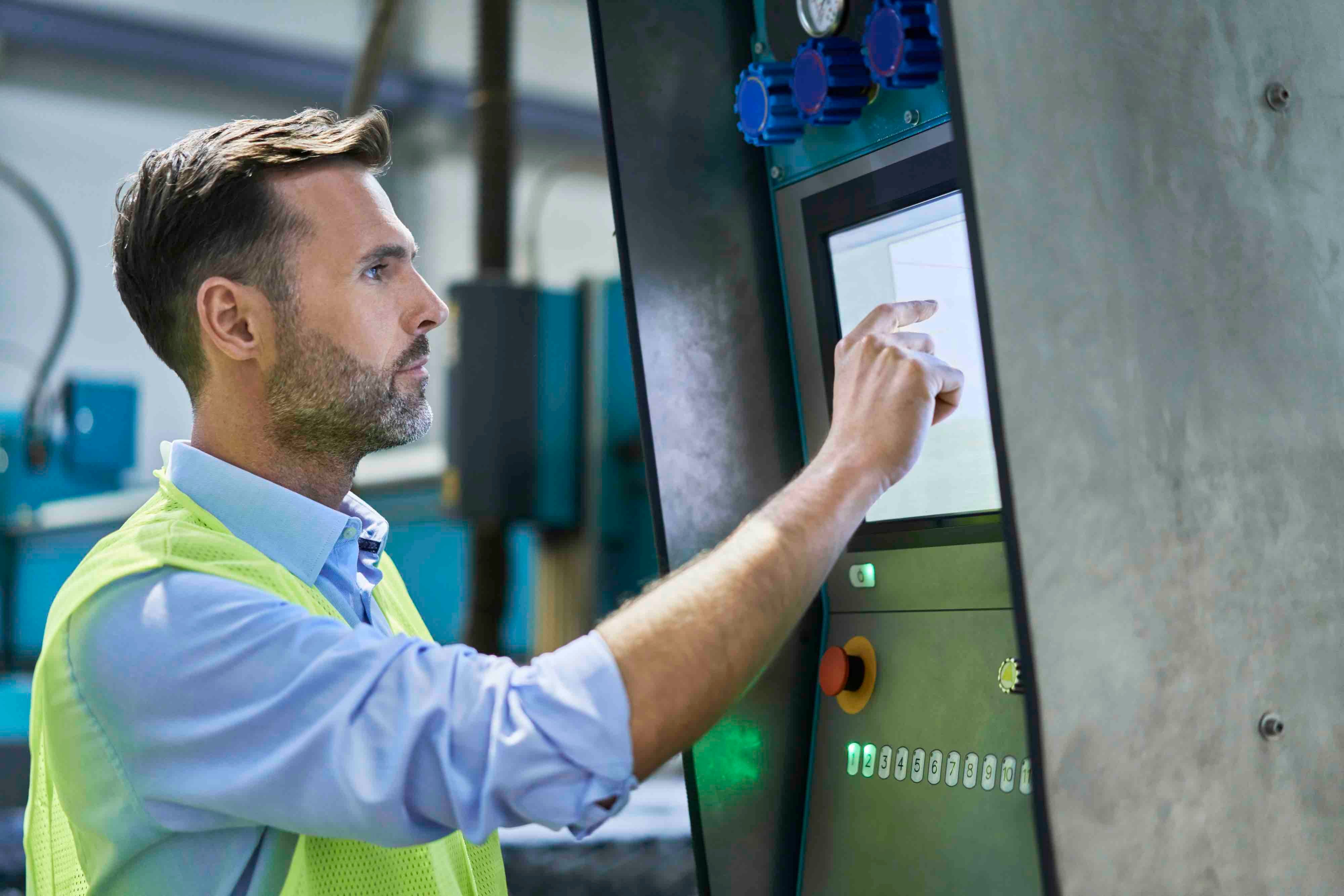 A male engineer is interacting with an industrial Panel PC in a kiosk or an industrial work station.